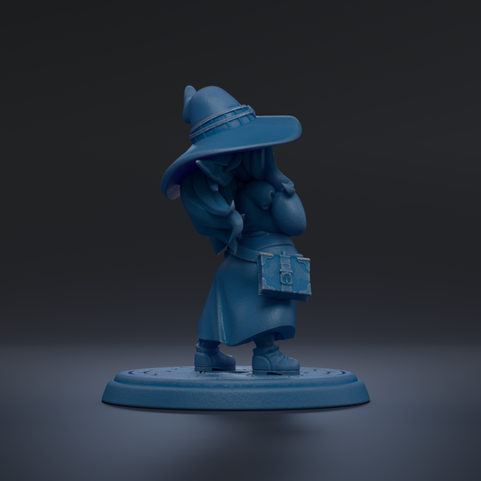 A blue figurine of a person wearing a hat and holding a book stands on a circular base against a dark background.