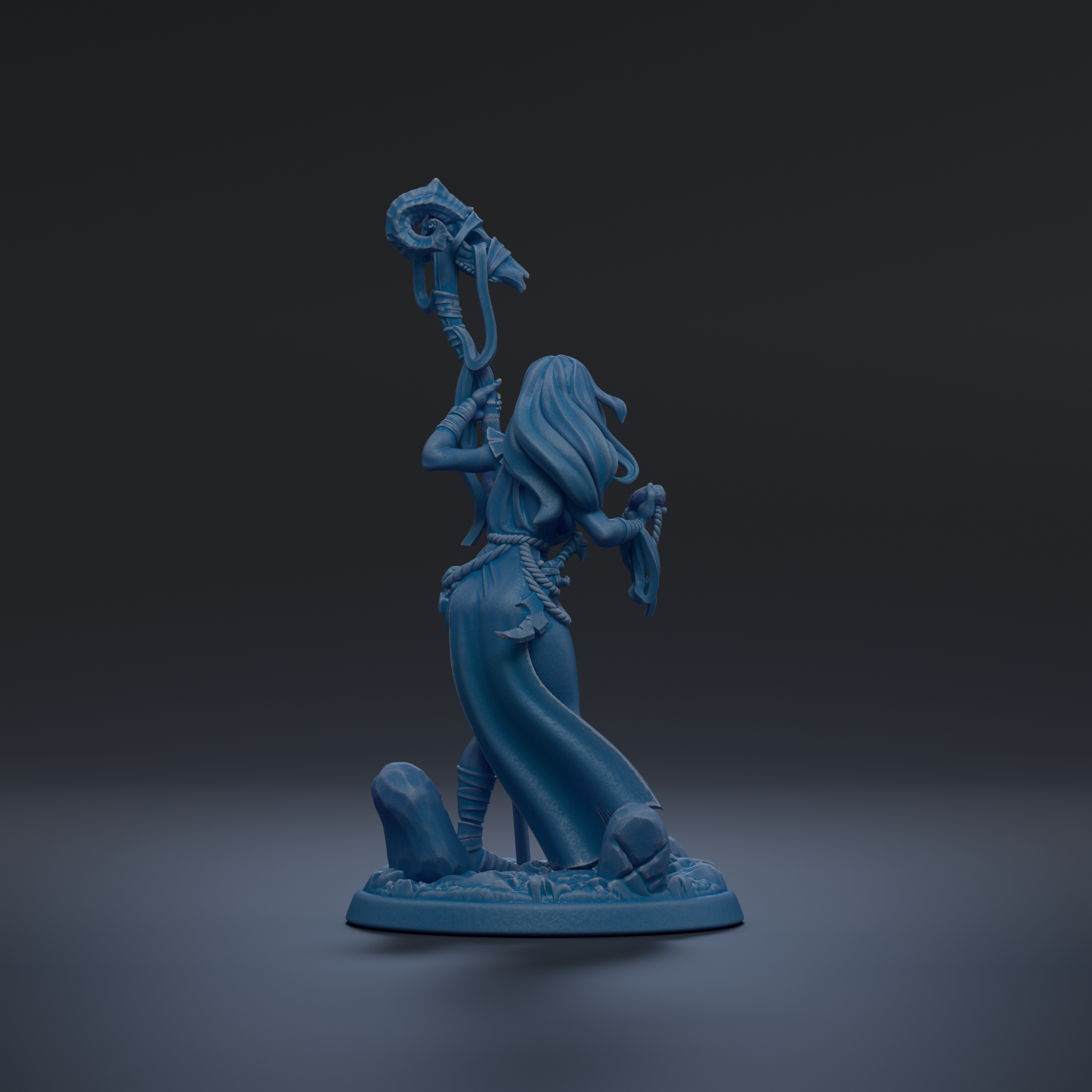 A blue figurine of a woman holding a staff and standing on a rock formation against a dark background.