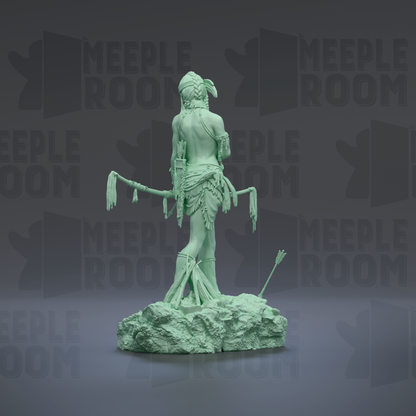 A green statue of a figure with a headdress and a staff, standing on a rock formation.