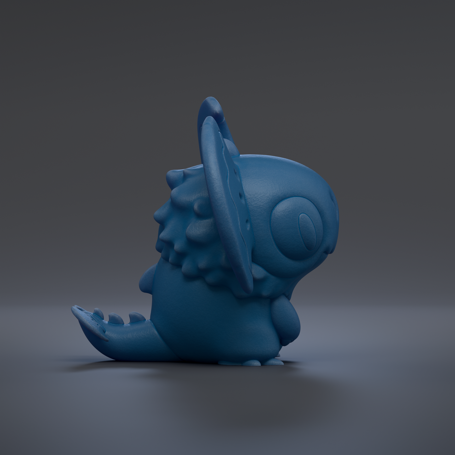 A blue, cartoon-like creature with a large head and long tail is sitting on a gray surface.