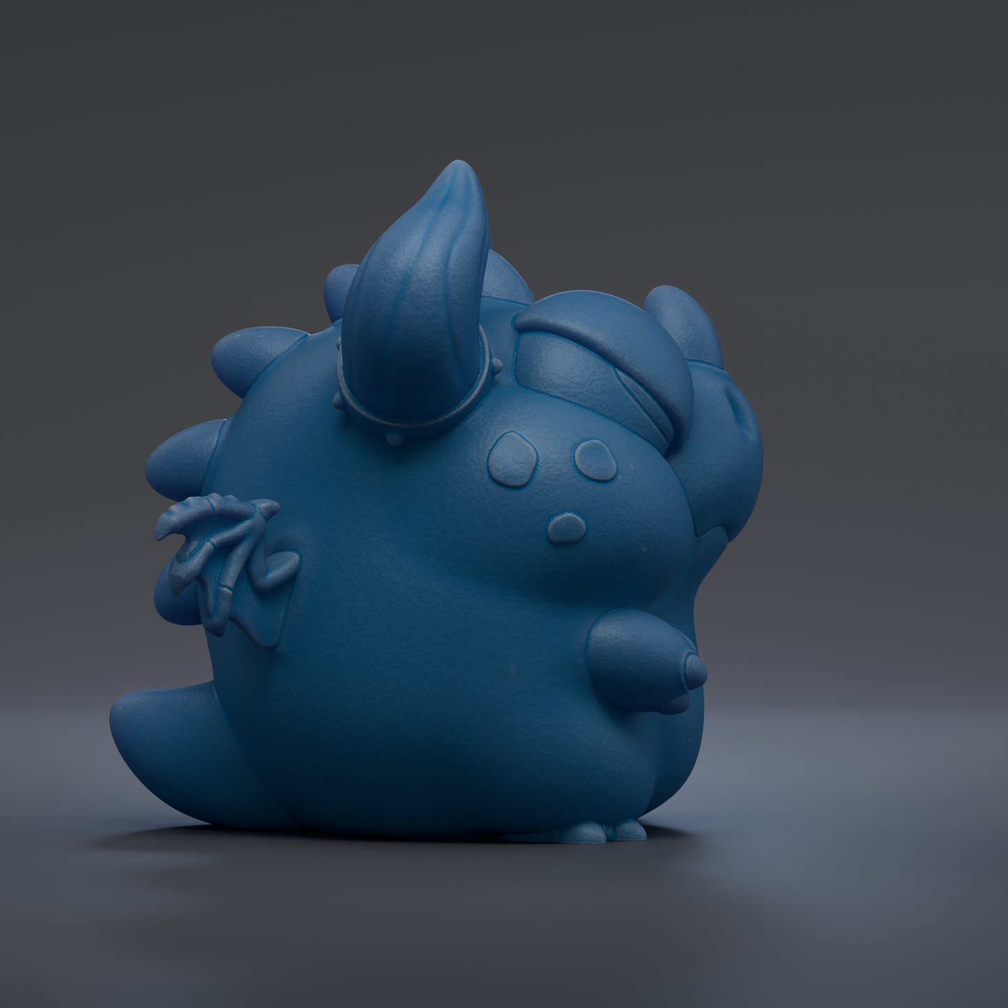 A blue, cartoon-like dragon figurine is sitting on a surface against a dark background.