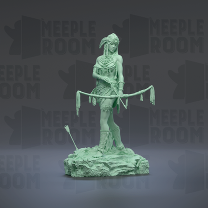 A green statue of a woman holding a bow and arrow, standing on a rock formation.