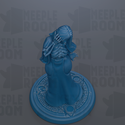 A blue figurine of a skeletal figure with a long neck and hands is displayed on a circular base with a patterned design.