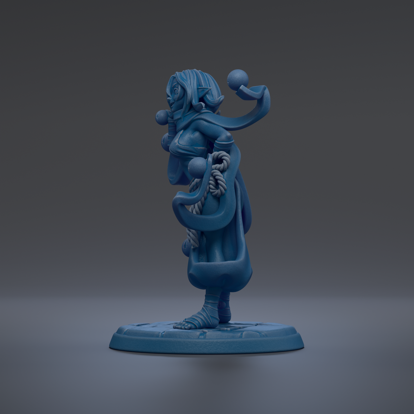 A blue figurine of a woman with a long, flowing dress and a headdress stands on a blue base against a dark background.