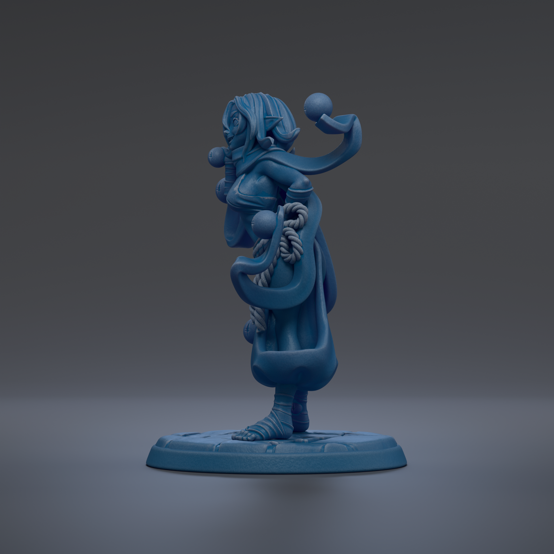 A blue figurine of a woman with a long, flowing dress and a headdress stands on a blue base against a dark background.