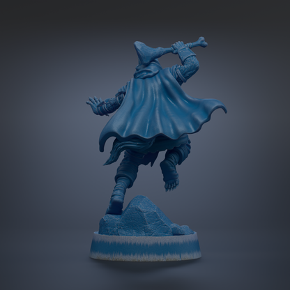 A blue statue of a figure in a cape, holding a weapon, standing on a rock formation.