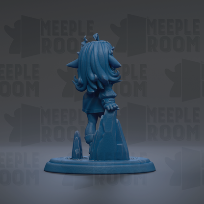 A blue figurine of a character with long hair and a crown, standing on a rock formation.