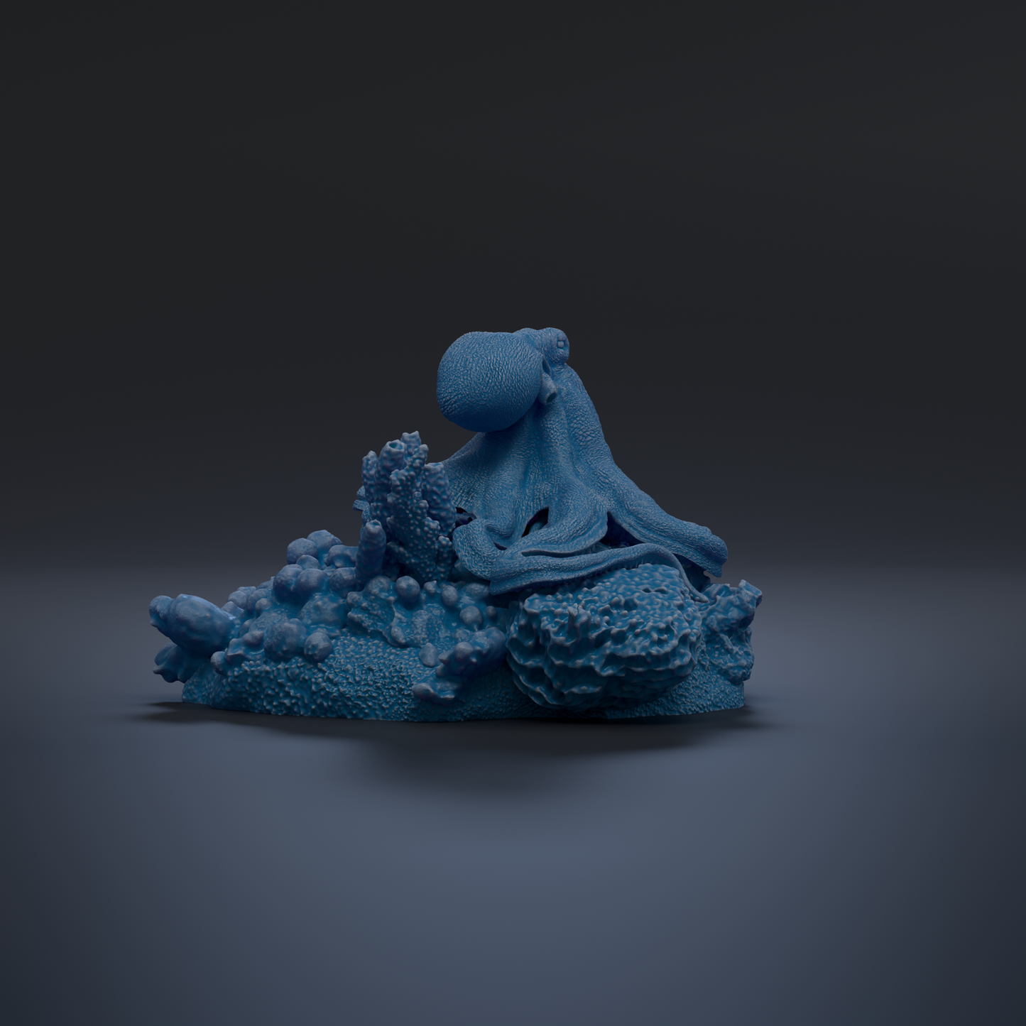 A blue octopus sculpture is displayed against a dark background, with its tentacles spread out in a relaxed pose.