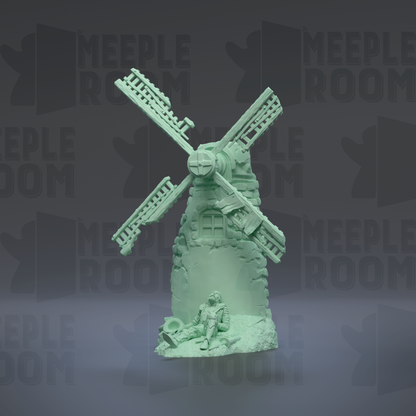 A green figurine of a windmill with a person sitting on a rock in front of it.