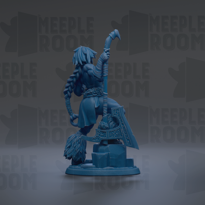 A blue figurine of a warrior figure holding a sword and shield, standing on a rock formation.