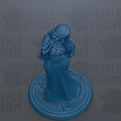A blue figurine of a skeletal figure with a long neck and a pointed head, standing on a circular base with a patterned design.
