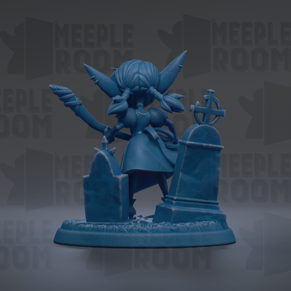 A blue figurine of a character with large ears and a cross on top, standing on a pedestal with a cross and a gravestone.