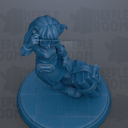 A blue figurine of a person sitting on a blue platform, holding a suitcase and wearing glasses.
