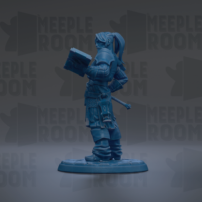 A blue figurine of a person holding a book, standing on a base.
