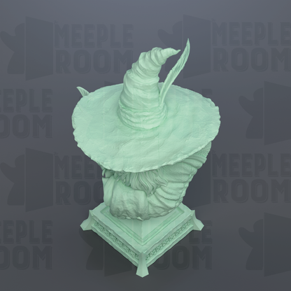 A green statue of a wizard wearing a pointed hat, sitting on a pedestal.