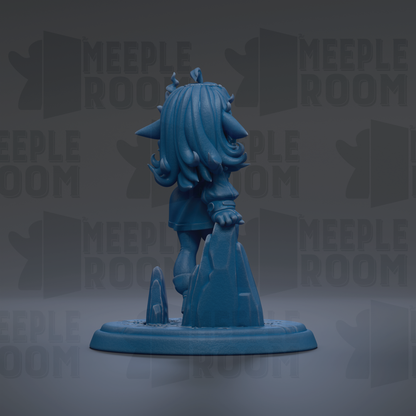 A blue figurine of a character with long hair and a pointed hat, standing on a rock formation.
