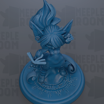 A blue figurine of a fantastical creature with a large head and flowing hair, holding a book and standing on a circular base with intricate designs.