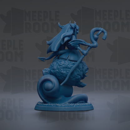 A blue figurine of a woman with horns and a long flowing hair, holding a staff and standing on a rock.