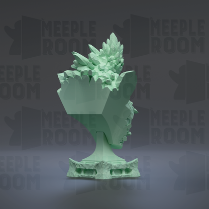 A green, 3D-rendered sculpture of a stylized head or face, with intricate details and a textured surface.
