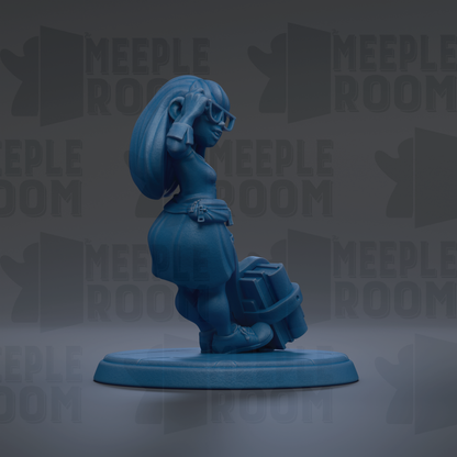 A blue figurine of a woman with long hair and glasses is standing on a blue base, holding a suitcase.