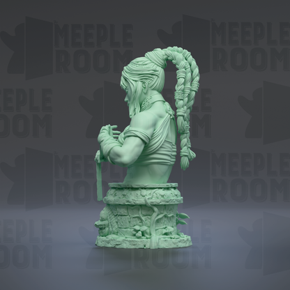A green statue of a woman with braided hair and a long ponytail, sitting on a pedestal and holding a weapon.