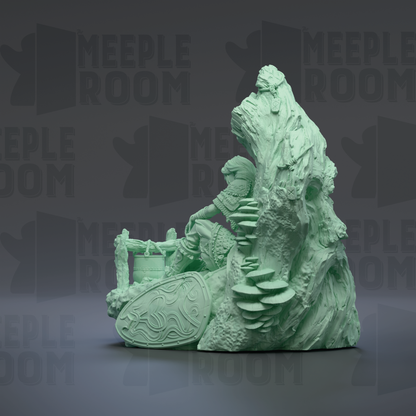 A green, sculpted figure of a person sitting on a rock formation, with a shield and other decorative elements.
