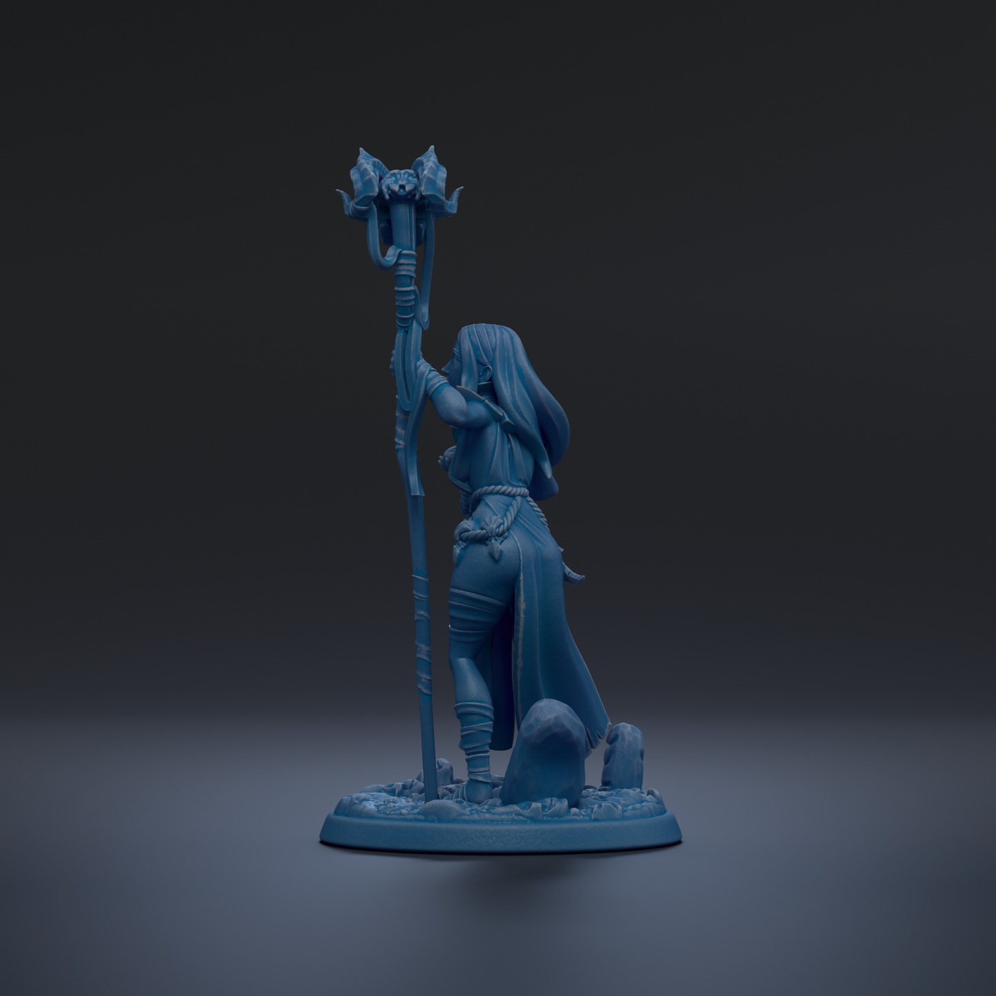 A blue figurine of a woman holding a staff and standing on a base with rocks.