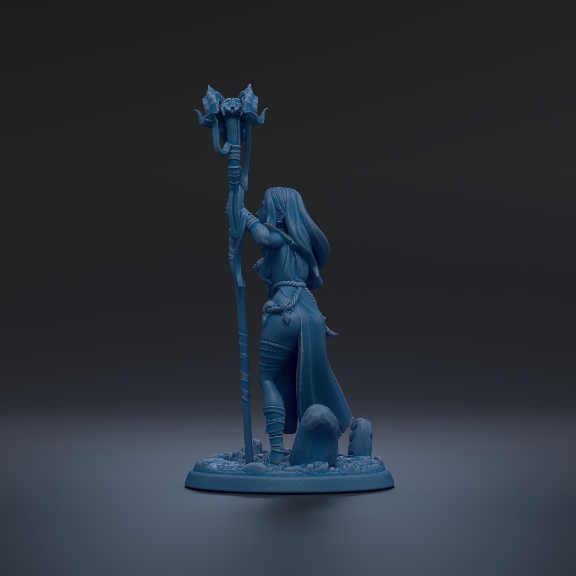 A blue figurine of a woman holding a staff and standing on a base with rocks.