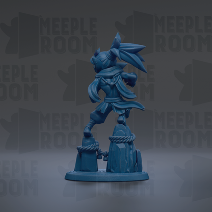 A blue figurine of a character with a flowing cape and a large headdress, standing on a rock formation.